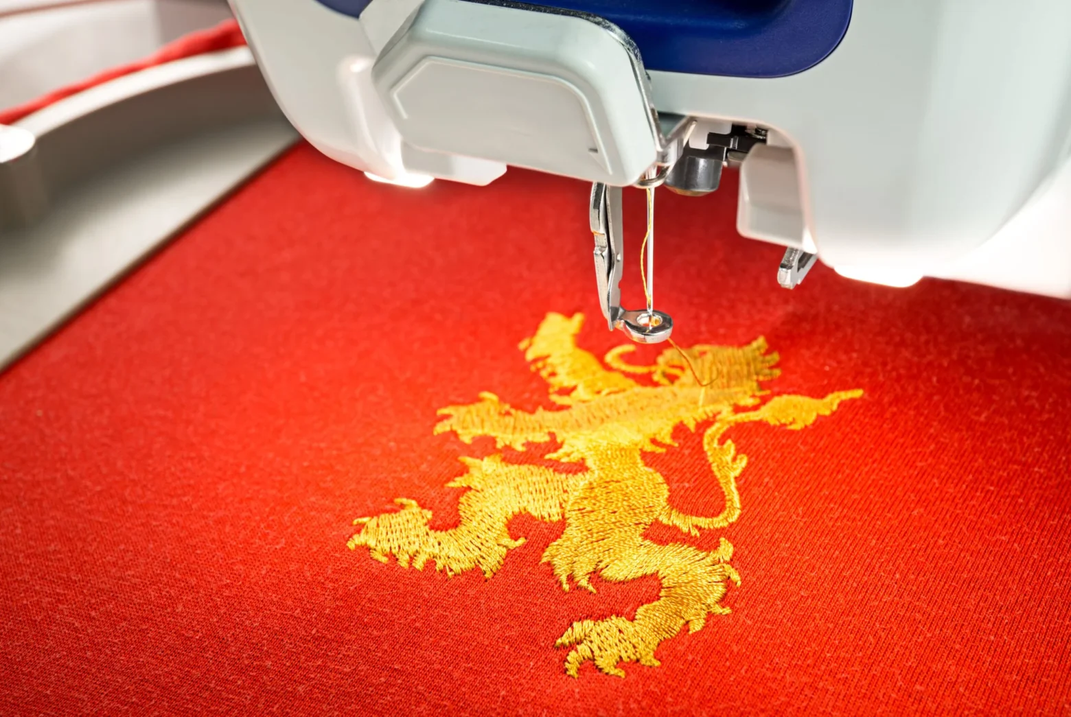 stickmaschine-und-goldener-loewe-auf-rotem-baumwollstoffhemd-scaled